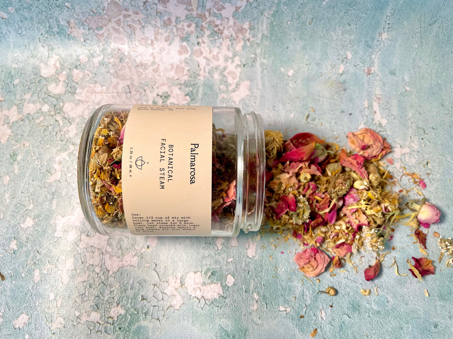 clear glass jar of ingredients of botanical facial steam spilling out of the jar
